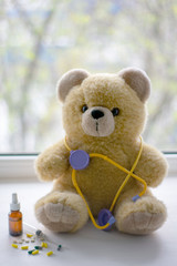 Cute teddy bear with a phonendoscope next to pills in the pediatric healthcare concept