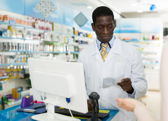 Naklejka na ściany i meble African American male pharmacist reading prescription of customer