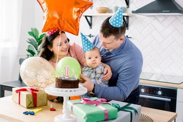 family, holidays and people concept - mother, father with chocolate cake wit number 1 and happy little son at home birthday party