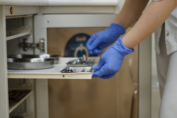 hands in blue gloves holding dental tools from the locker Bura syringe