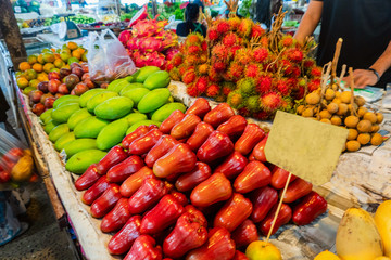 A traditional Thai market stall selling apples and other tropical fruits
