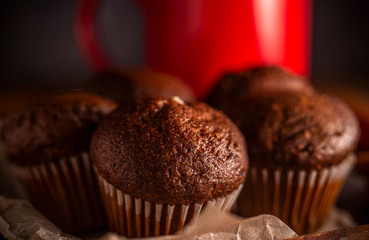 Fresh chocolate muffins and cinnamon sticks on rustic wooden background