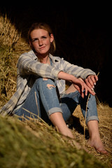 Naklejka na ściany i meble young beautiful girl with freckles in denim overalls in the hayloft