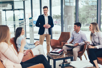 Business team working on new project and smiling. Man and women sitting together in modern office for project discussion.