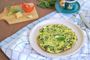 Breakfast, omelet with nettles on a white clay plate. Healthy food. Food from wild herbs.