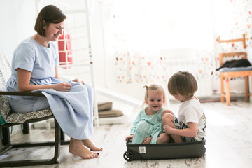 Obraz premium Children are sitting in suitcase near mother