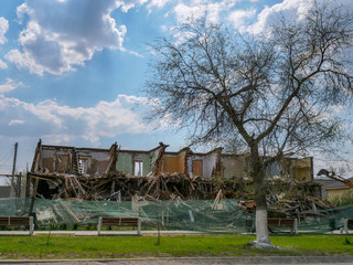 Destruction of walls of old building and cleaning of construction debris with bucket of...