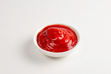 Ketchup in white plate on white background.