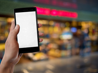 hand holding and using and touch screen smart phone on blurred background at supermarket store
