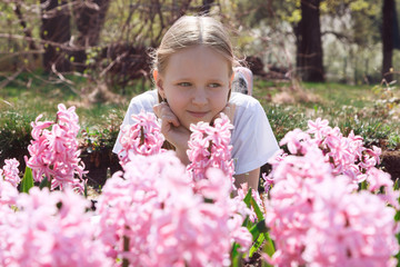 Beautiful slim little girl teenager walks in the flowered garden. Children's portrait. Spring. The...