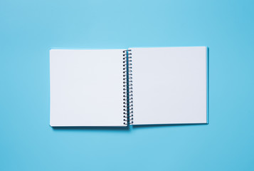 Blank open blue note book on blue background with shadow