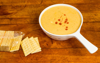 Cheese and Broccoli Soup sprinkled with Hot Sauce and served with Crackers on Rustic BG