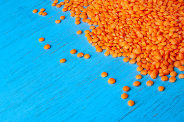 Fototapeta na wymiar Red lentils on a blue wooden background. Background with a lot of lentils and place for text.