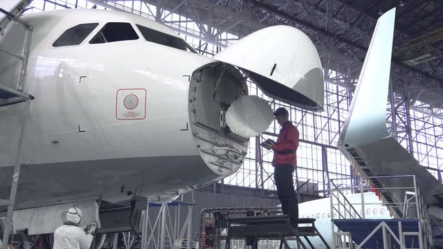 Engineer repairs locator passenger aircraft. The plane in the hangar, antenna repair. Aviation. Production of passenger Airliners. 4K