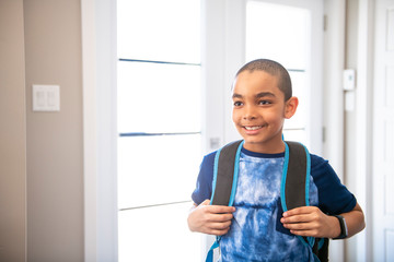 A child boy coming home passing through the door after school