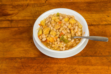 Overhead View of Cornbread Crumbled into Bowl of Bean Soup on Rustic Wood Table