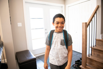 A child boy coming home passing through the door after school