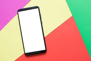 Smartphone with white screen on colored paper. Top view. 