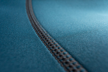 Close up of stitching along the seam of a blue neoprene scuba diving wetsuit - obrazy, fototapety, plakaty