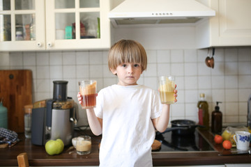 Boy with fresh fruit juice in real kitchen