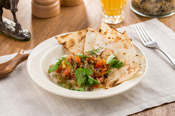 Baked vegetables with parsley and lavash bread on wooden table