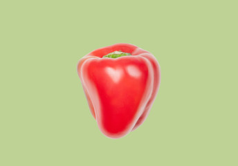 Red pepper levitate in air on green pastel background. Concept of vegetable levitation.