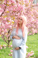 Fototapeta na wymiar Pregnant woman with blooming tree on background. Motherhood, pregnancy and expectation concept.