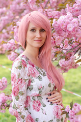 Fototapeta premium Pregnant woman with pink hair with her hands over tummy. Motherhood, pregnancy