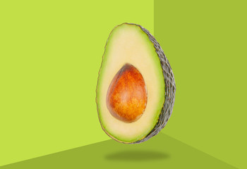Avocado levitate in air on green background. Concept of vegetable levitation.