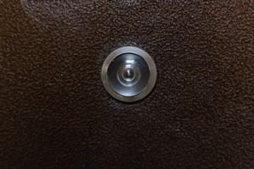 door peephole on metal brown front door close-up