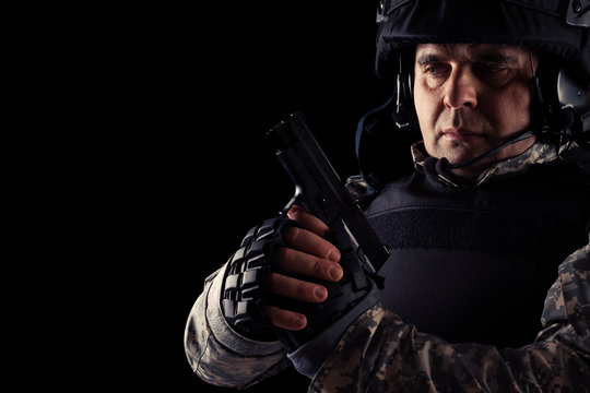 Soldier aiming with black pistol. Image on a dark background. 