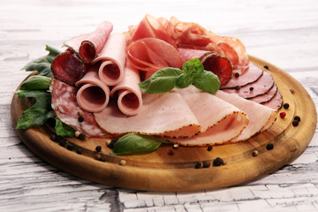 Food tray with delicious salami, pieces of sliced ham, sausages,salad and vegetable. Meat platter with selection