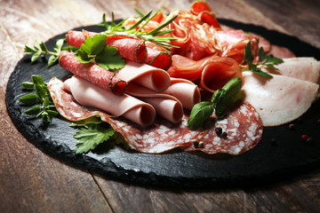 Food tray with delicious salami, pieces of sliced ham, sausages,salad and vegetable. Meat platter with selection