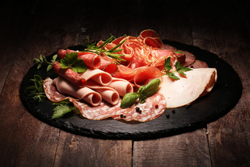 Food tray with delicious salami, pieces of sliced ham, sausages,salad and vegetable. Meat platter...