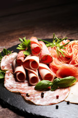 Food tray with delicious salami, pieces of sliced ham, sausages,salad and vegetable. Meat platter with selection