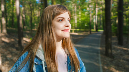 Naklejka premium Calm beautiful smiling young woman enjoying fresh air , relaxing , feeling alive, breathing, dreaming. Copy space, green park nature background. Side view portrait