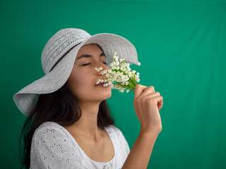 Jeune fille au chapeau qui sent du muguet le 1er mai