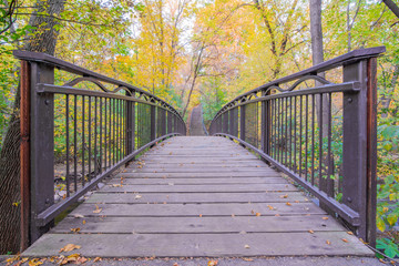Pedestrian bridge over creek in Minneapolis - in fall with autumn colors in tree leaves - yellows and greens