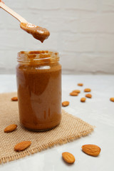 Almond butter in a jar on neutral background, selective focus
