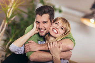 Loving young couple hugging and relaxing on sofa at home