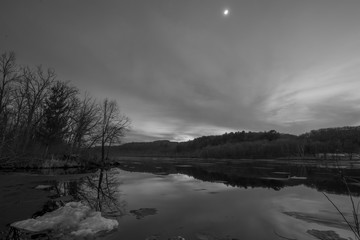 Black and white wide angle landscape view of the vast St. Croix River on a frosty winter sunset / early evening - river separating Wisconsin and Minnesota - beautiful clouds and ice chunks in river