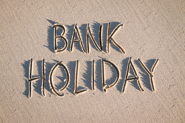 Bank Holiday message handwritten on the textured sand of an empty beach