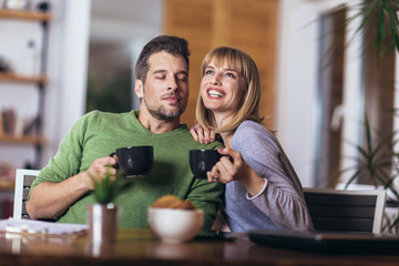 Couple talking in the night in the living room at home and drink tea