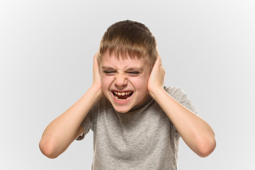 Boy closed his ears with his hands and shouts furiously. Naughty schoolboy. Isolate