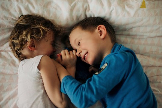 brother and sister laughing and having sibling fun at home in bedroom