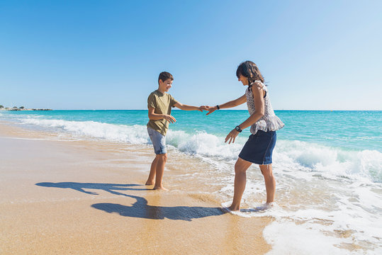 Front view of mom and son enjoying together while standing on seashore