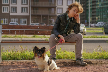 sad lonely guy sitting on a bench with his dog. the difficulties of adolescence in communication...