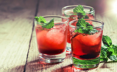 Alcoholic cocktail with white rum, red vermouth, mint and ice cubes, wooden table, selective focus