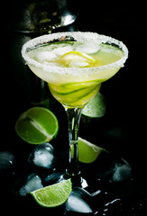 Lime Daiquiri cocktail in glass, black bar counter background, selective focus
