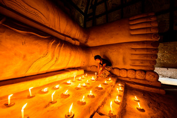 Asian girl lighting prayer candles in Buddhist temple